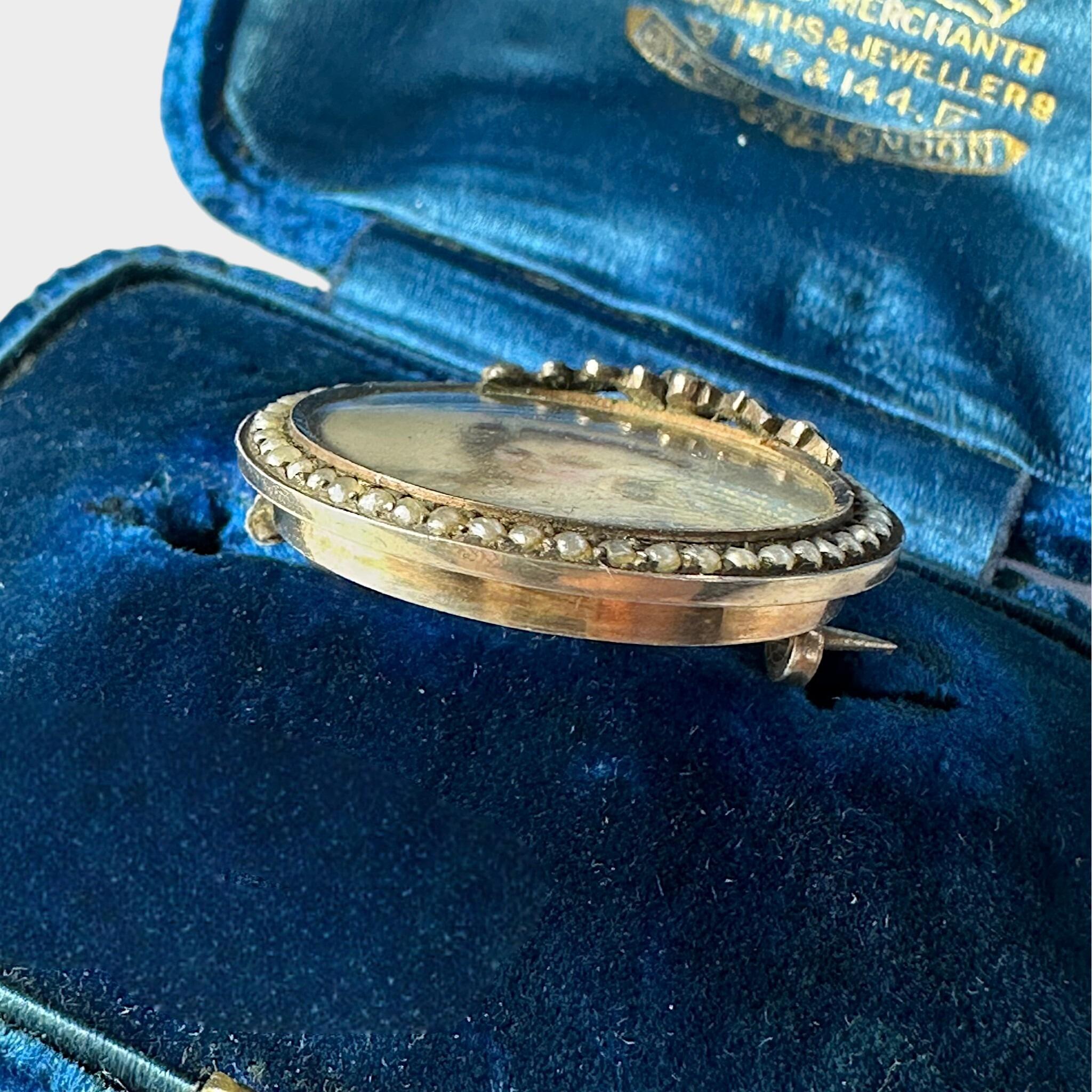 side view of Georgian Marie Antoinette & Silver Seed Pearl Portrait Brooch laying on blue antique box