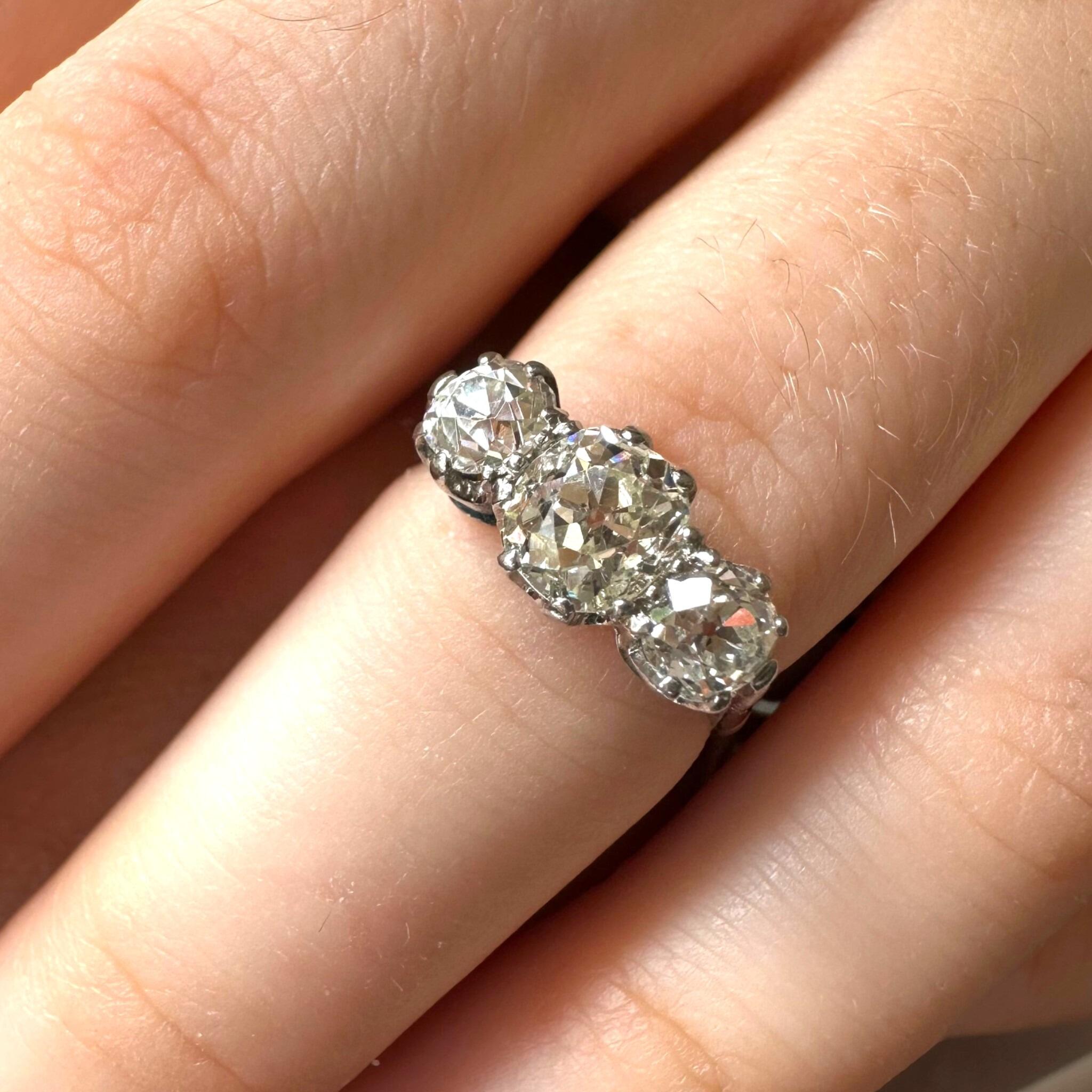 Antique Platinum Old Cushion Cut Diamond Trilogy Ring worn on models hand