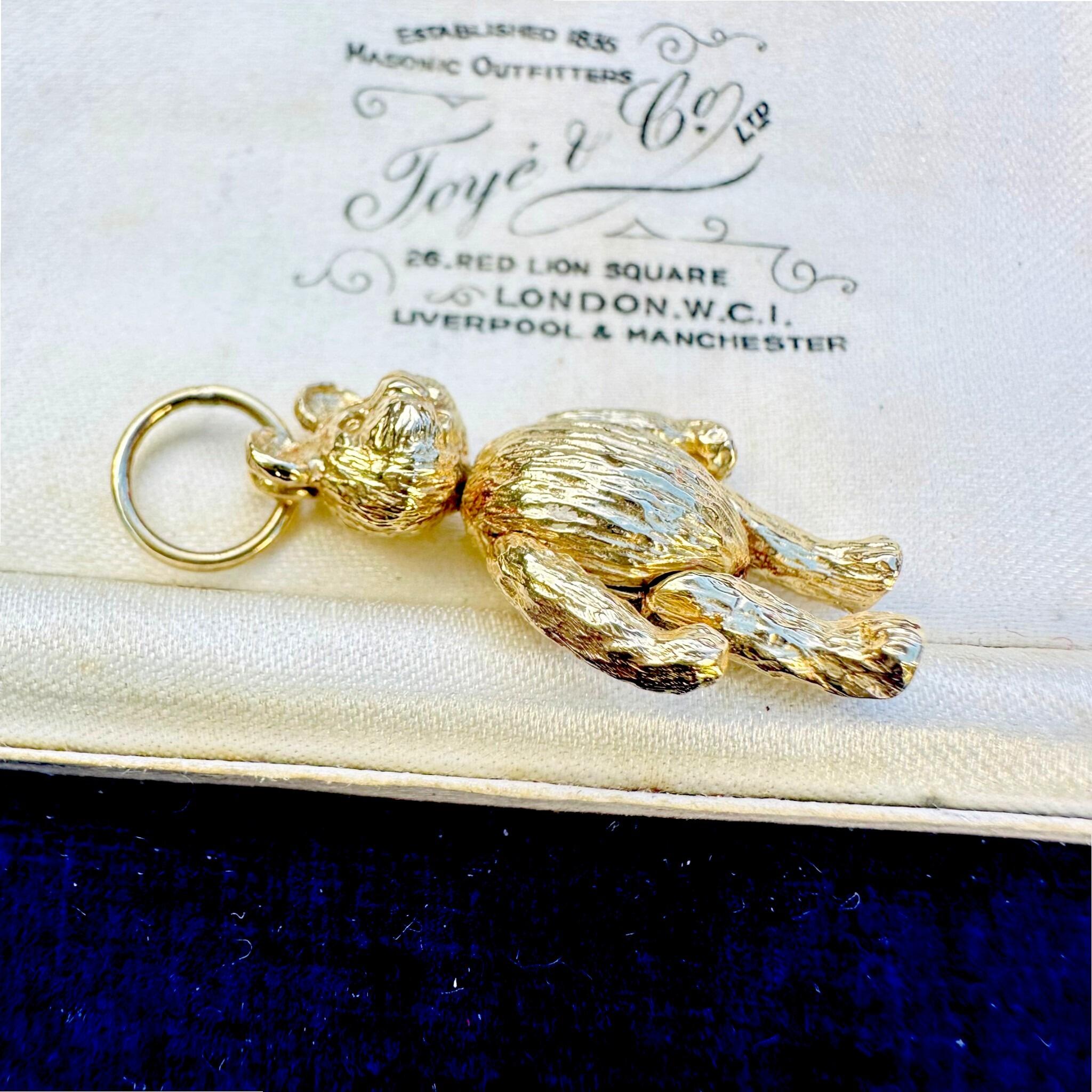 side profile of Vintage Gold Articulated Teddy Bear Charm Pendant, laying on antique box