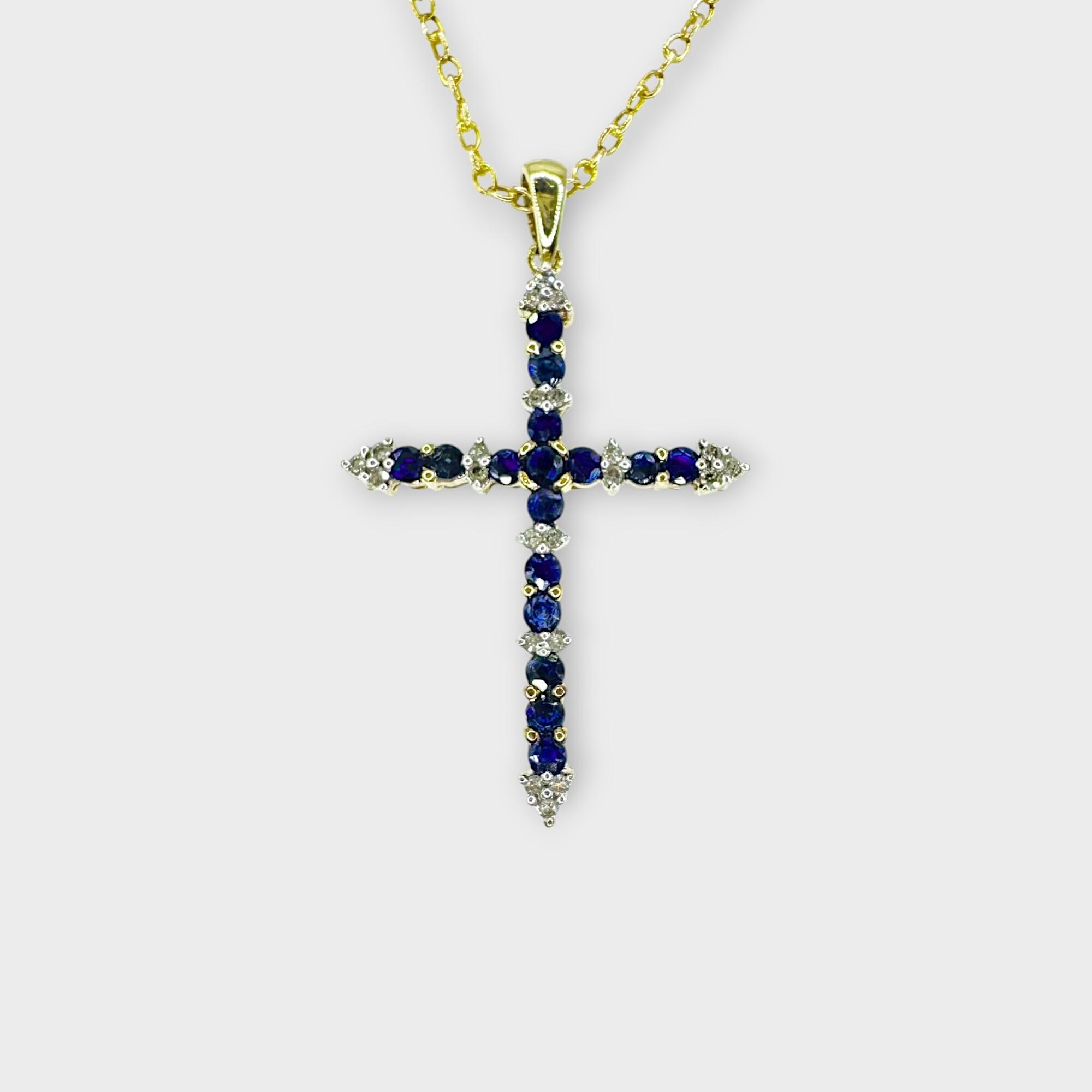Sapphire and diamond cross in 9ct yellow gold on grey background.