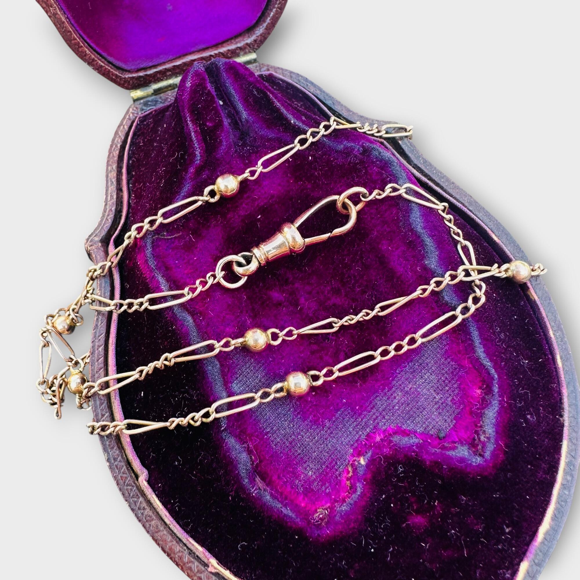 Antique 9ct rose gold Figaro link and ball chain displayed on a purple antique box