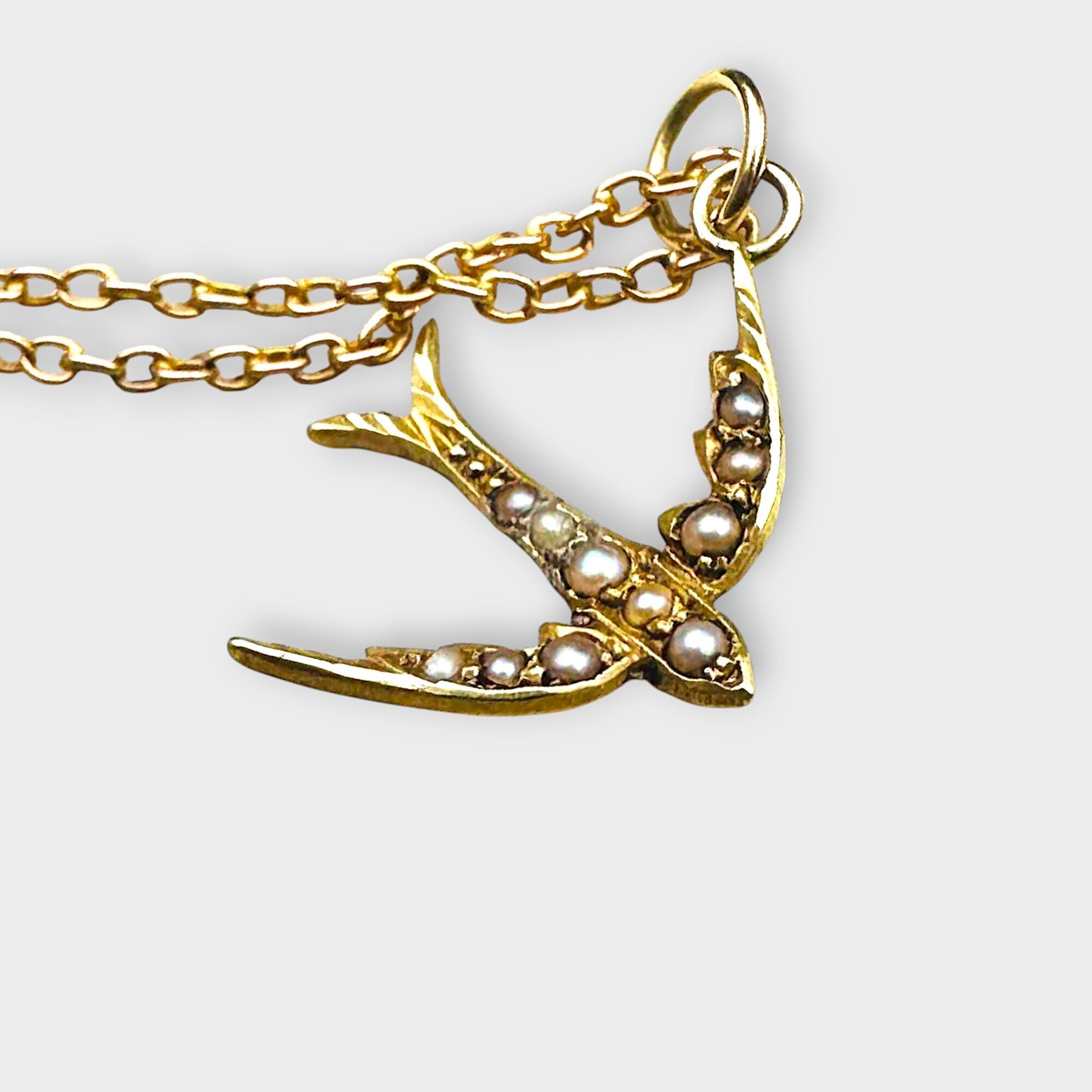 15k gold antique pearl swallow pendant / charm on short chain on grey background.