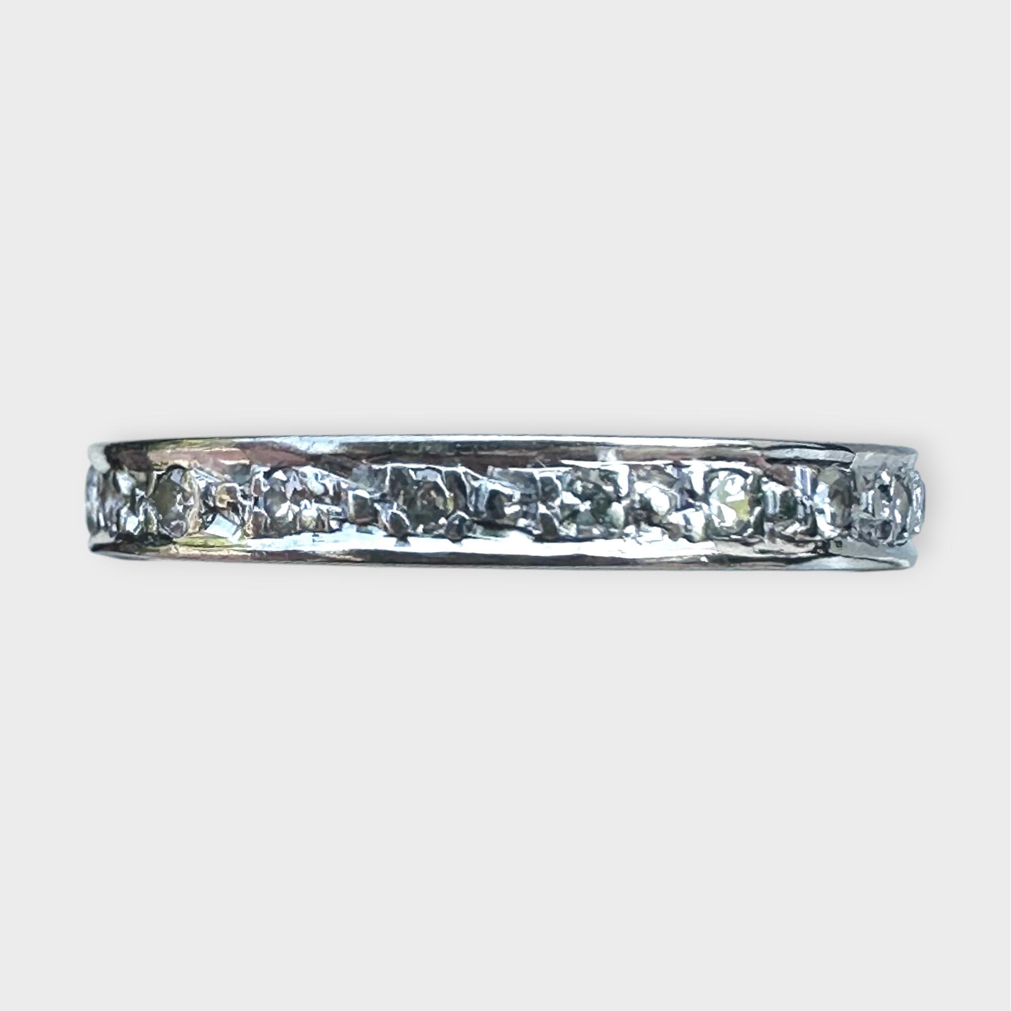 Art Deco full eternity ring in 18ct white gold, set with diamonds all around the band on grey background.
