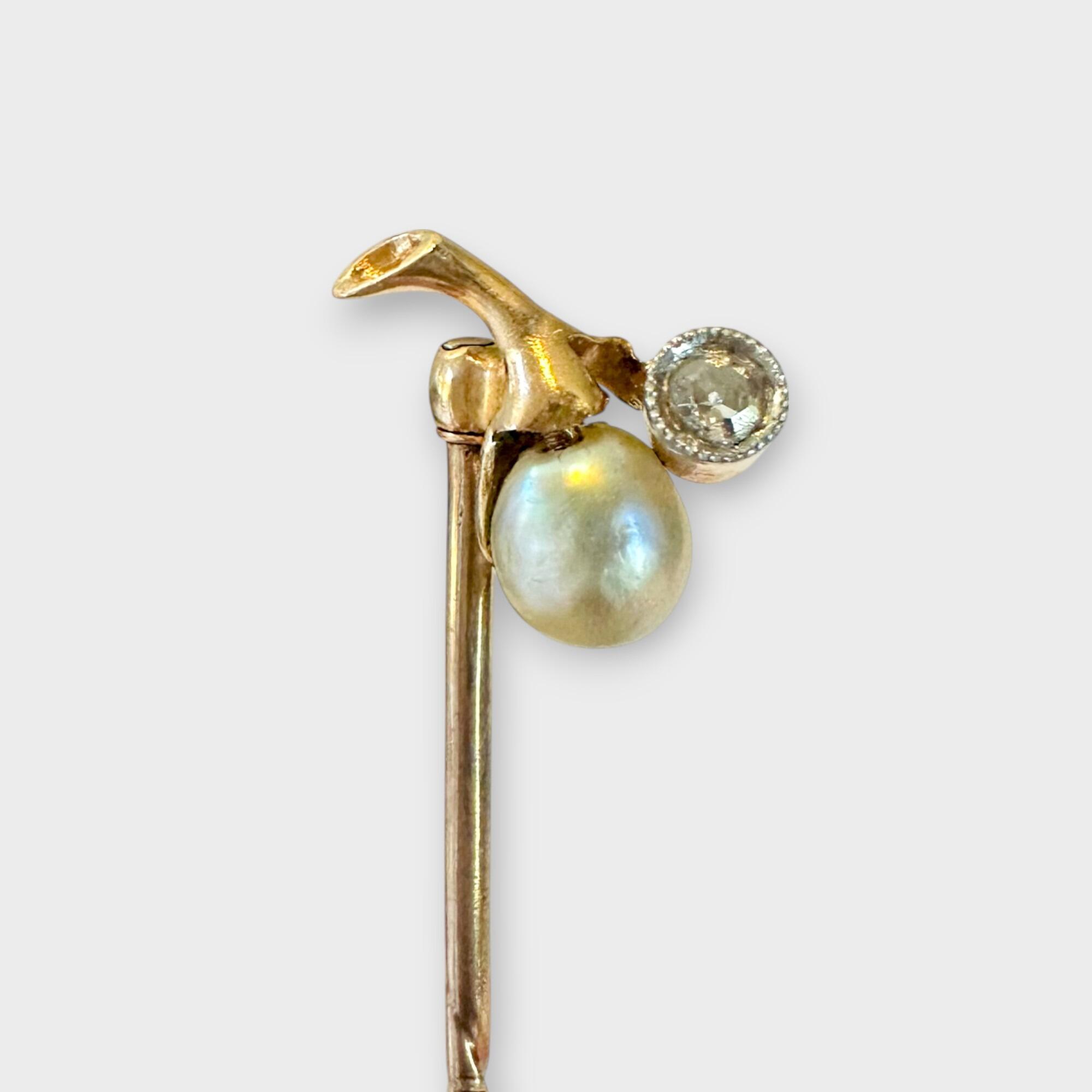 Art Nouveau stick pin in 15k gold with pear-shaped pearl and diamond berry design on grey background.
