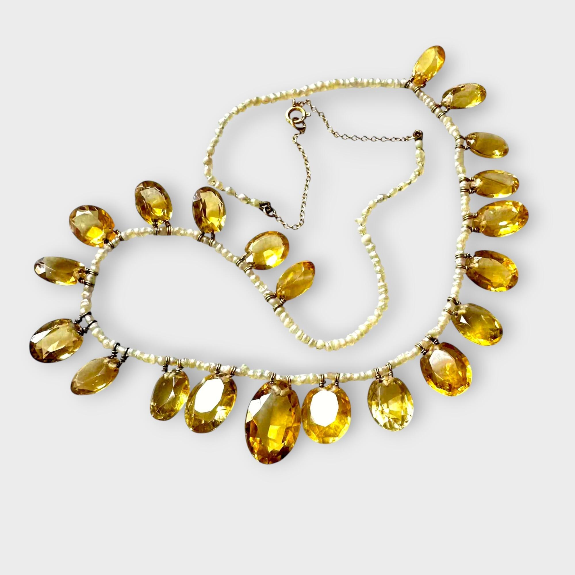 Close-up of faceted golden-yellow citrine gemstones and natural pearls on antique gold chain