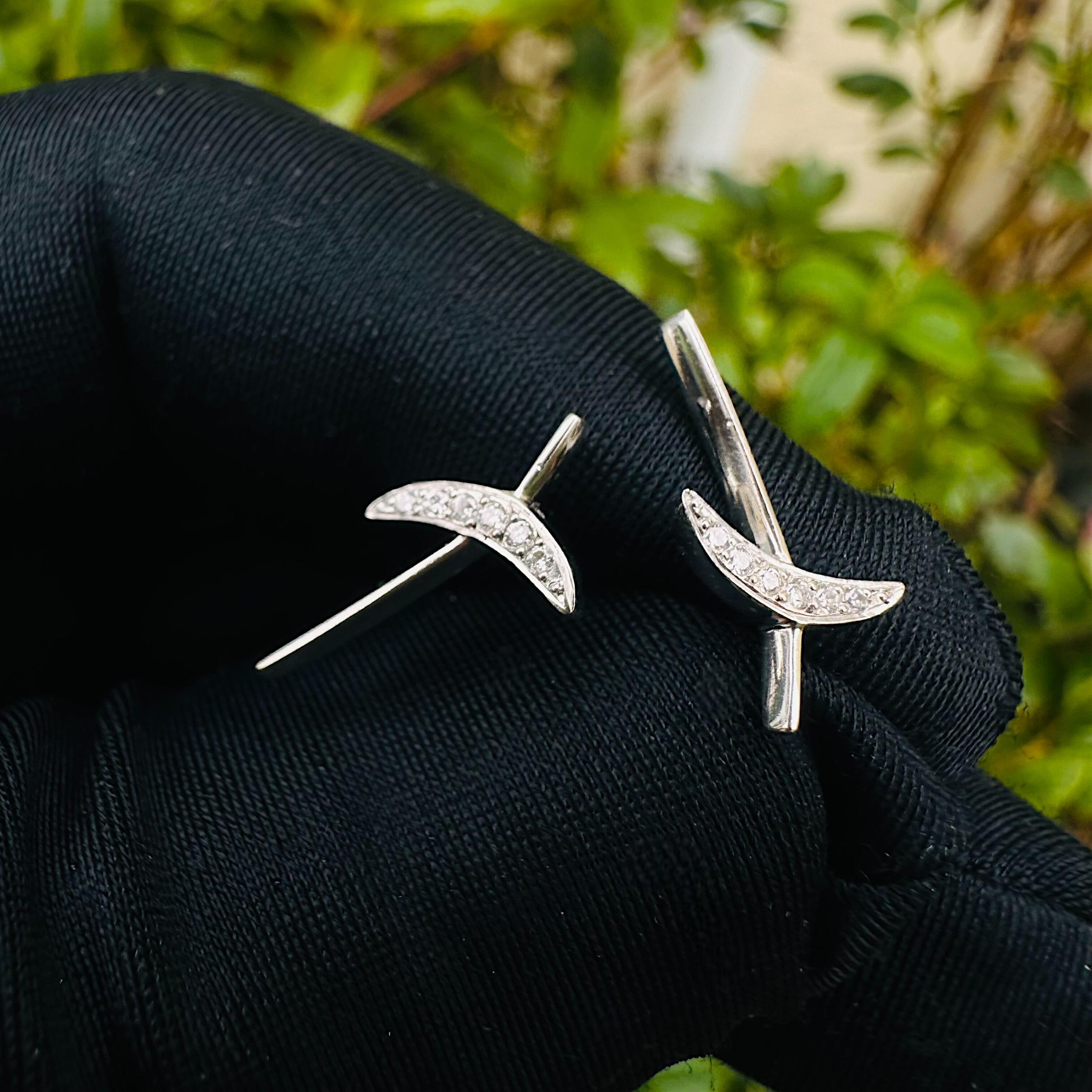 Platinum & Diamond Kiss Earrings held in black glove in garden