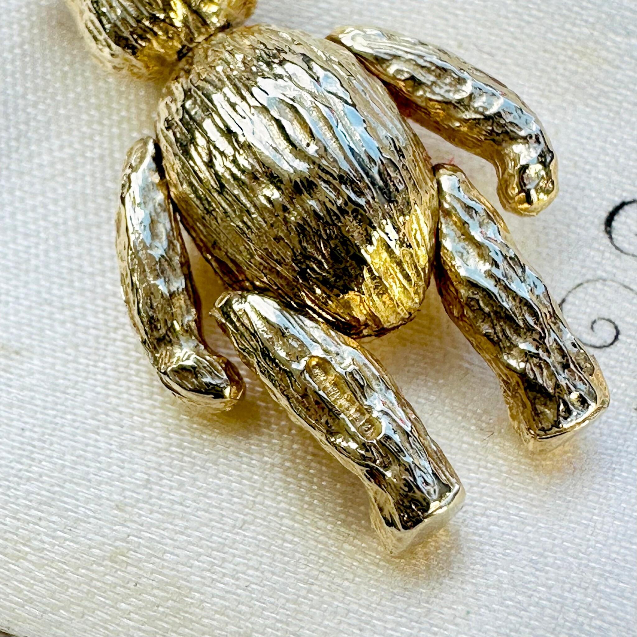 close up of Vintage Gold Articulated Teddy Bear Charm Pendant, laying on antique box