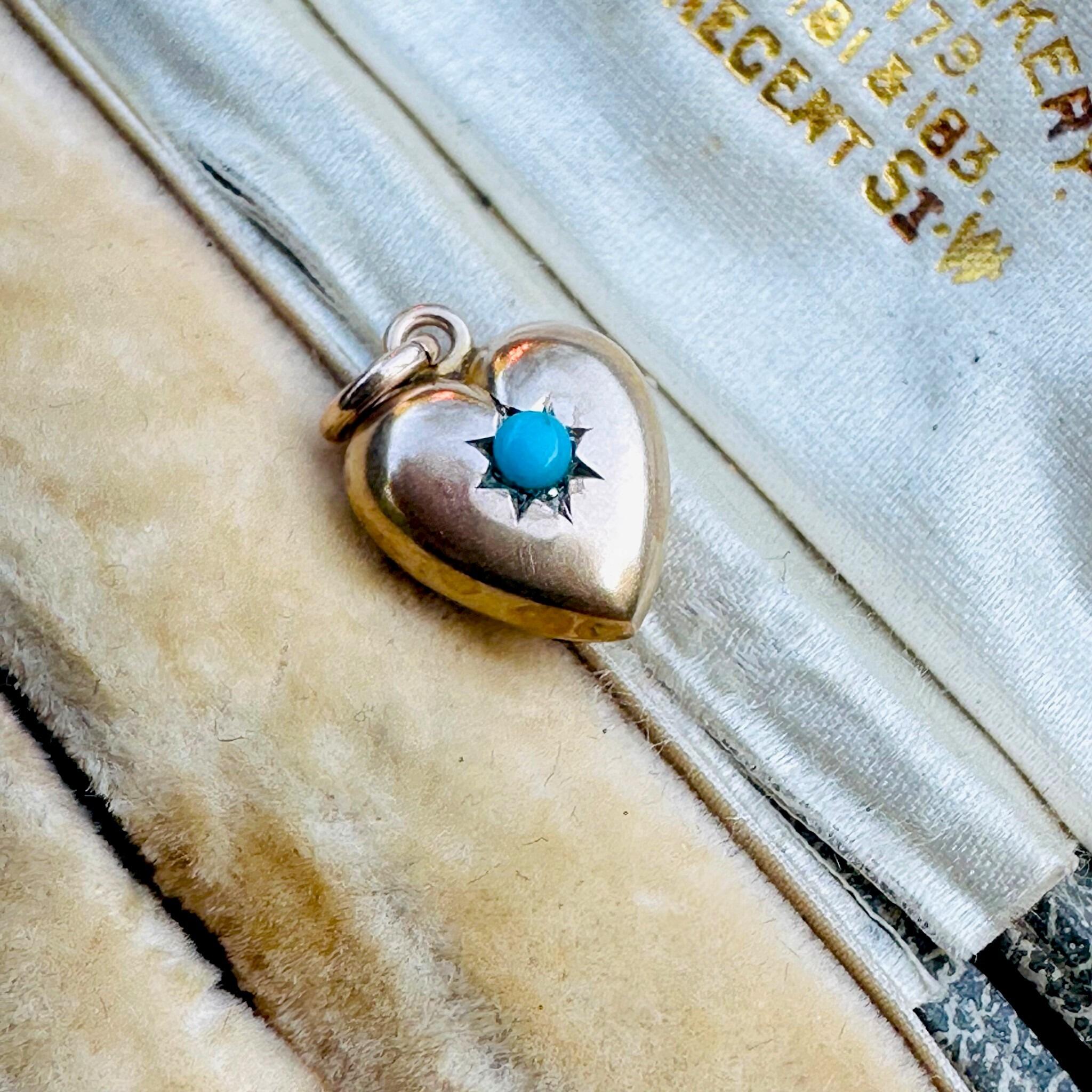 side view Antique Art Deco, Gold & Turquoise Puffy Heart Pendant  laying on a antique box