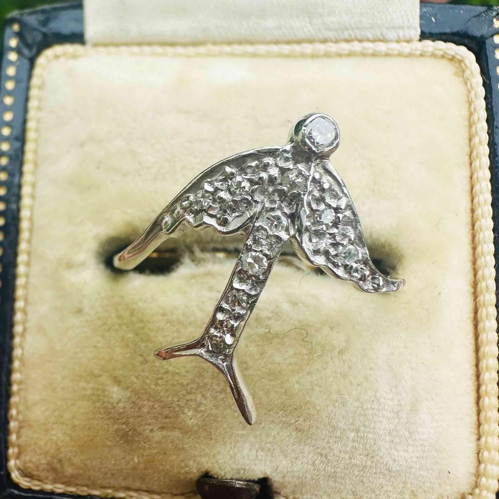 Artistic 14k gold swallow ring featuring diamond-encrusted wings and tail in antique box, close up view.