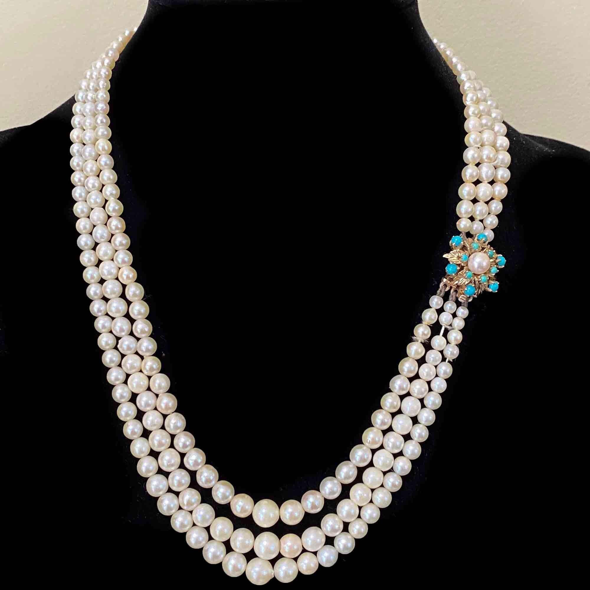 Front view of a vintage 1960s three-row cultured pearl necklace with a gold and turquoise clasp.