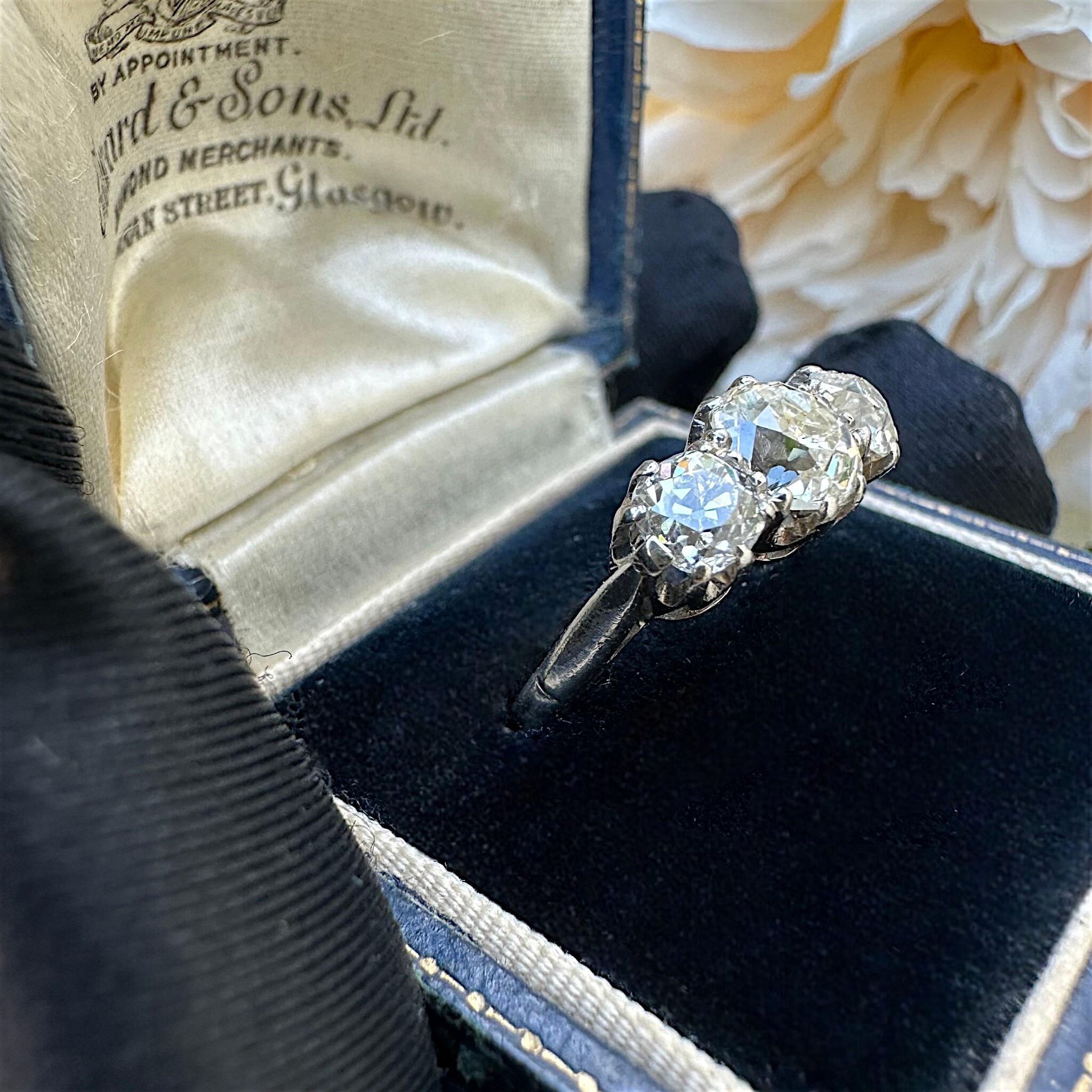 side view of Antique Platinum Old Cushion Cut Diamond Trilogy Ring displayed in antique box