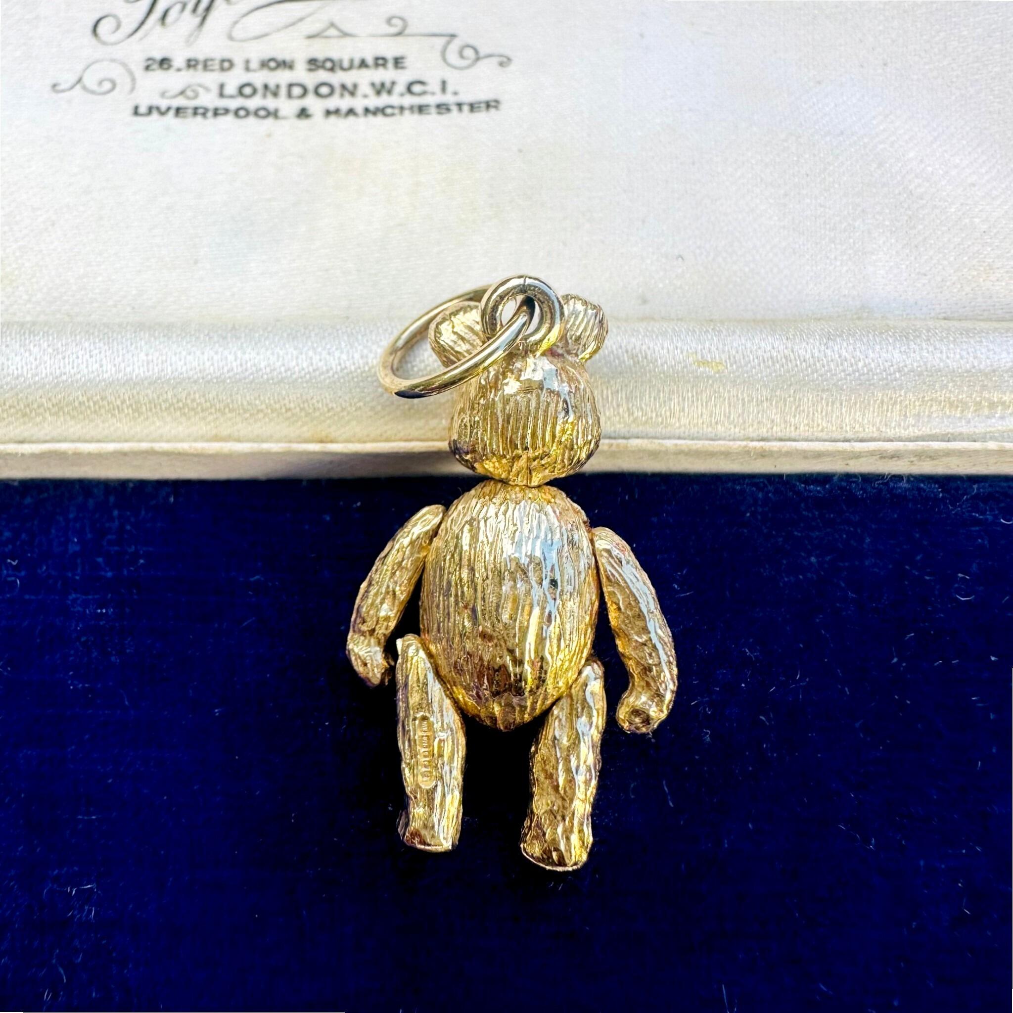 rear view of Vintage Gold Articulated Teddy Bear Charm Pendant, laying on antique box