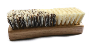 Scrubbing brush made of light natural wood. Led bristle side up with natural brown bristles to the left and cream bristles on the right.