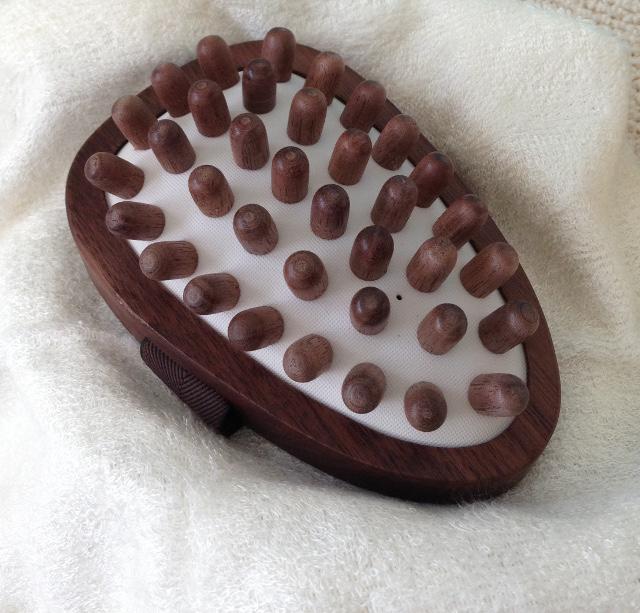 walnut wood cellulite massage led upright to show  wood pegs on a cream cushion base.