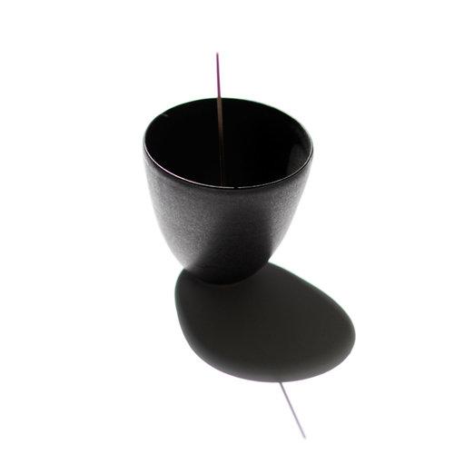 Black porcelain curved pot shown with incense stick inserted