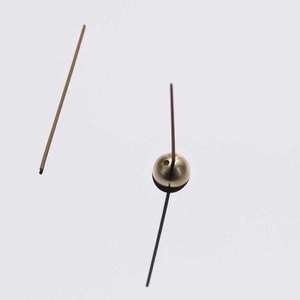 Small gold dome shaped incense holder, with incense stick inserted.