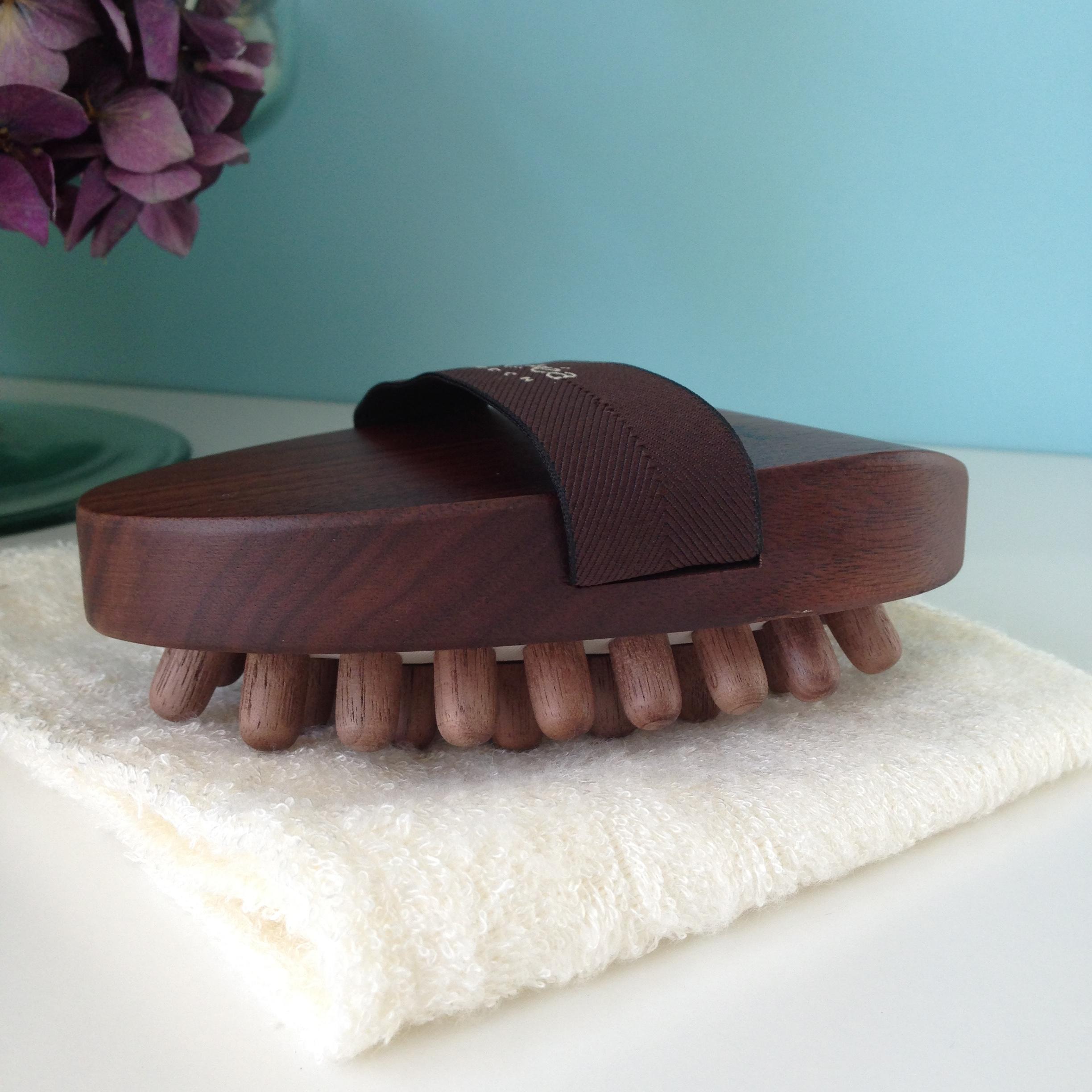 view of dark brown walnut wood cellulite massager face down on a cream flannel.