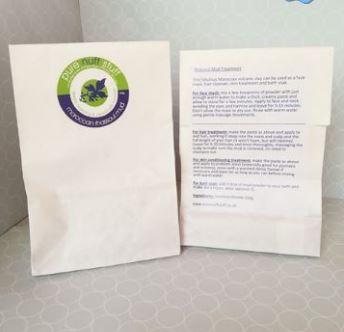 White paper bag with green and blue pure nuff stuff leaf logo on front showing moroccan rhassoul mud. Reverse of bag shown displaying usage instructions