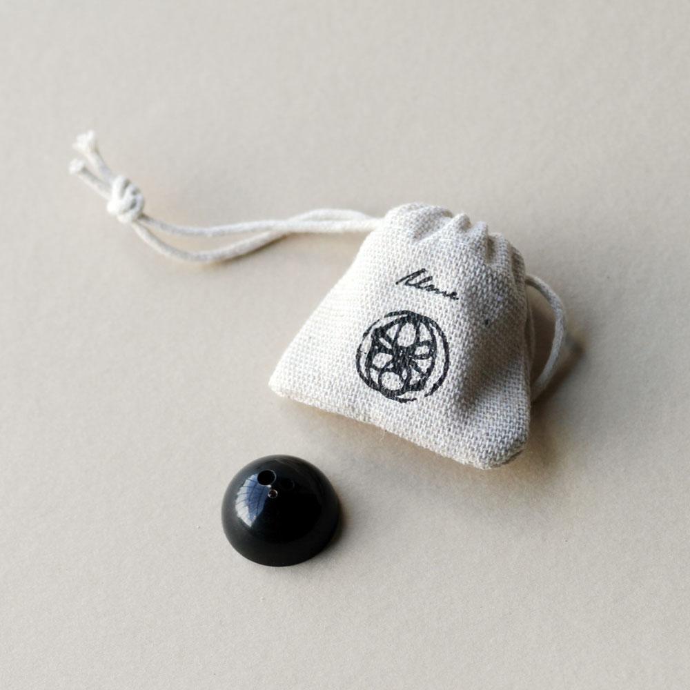 Small black metallic dome shaped incense holder shown with white cotton drawstring pouch.