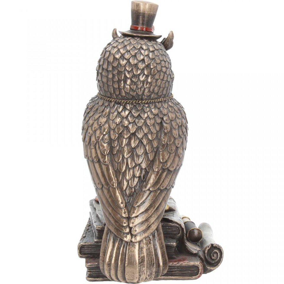 Standing on a stack of leather-bound books, this mechanical owl is almost the real thing. Metallic wings folded at their side, individual feathers riveted on, a red clock hangs from a gold chain around their neck. Eyes shaped like large red cogs have a golden shutter at the centre, and are topped with large brass eyebrows. Sitting on top is a small top hat with goggles sitting on top, while around the books, a map and some navigator’s tools are scattered. Cast in the finest resin before being painstakingly hand-painted, this Steampunk figurine is the perfect companion to have aboard your airship.