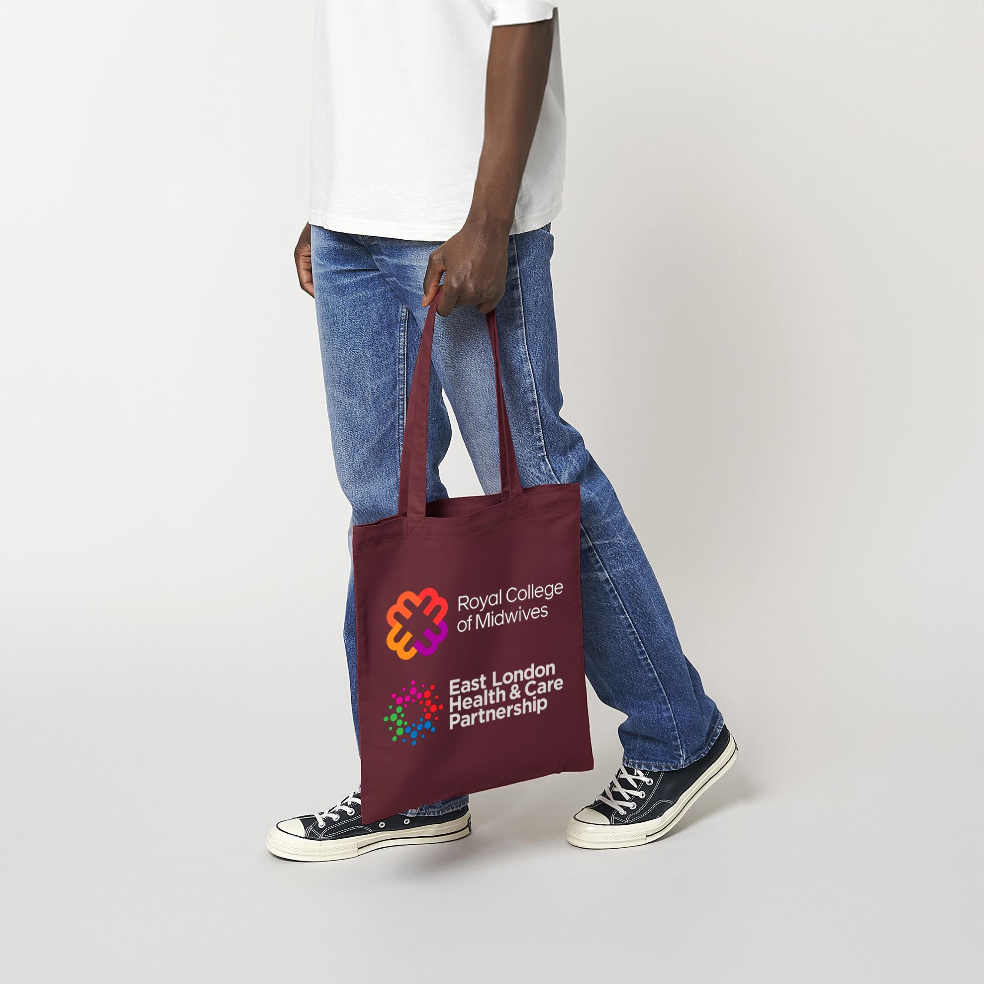 Burgundy coloured cotton shopping bag being held by a man