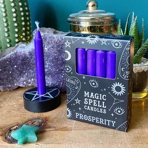 Box of 12 Purple 'Prosperity' Spell Candles on a wooden table, with a single candle in a round holder and other decor.