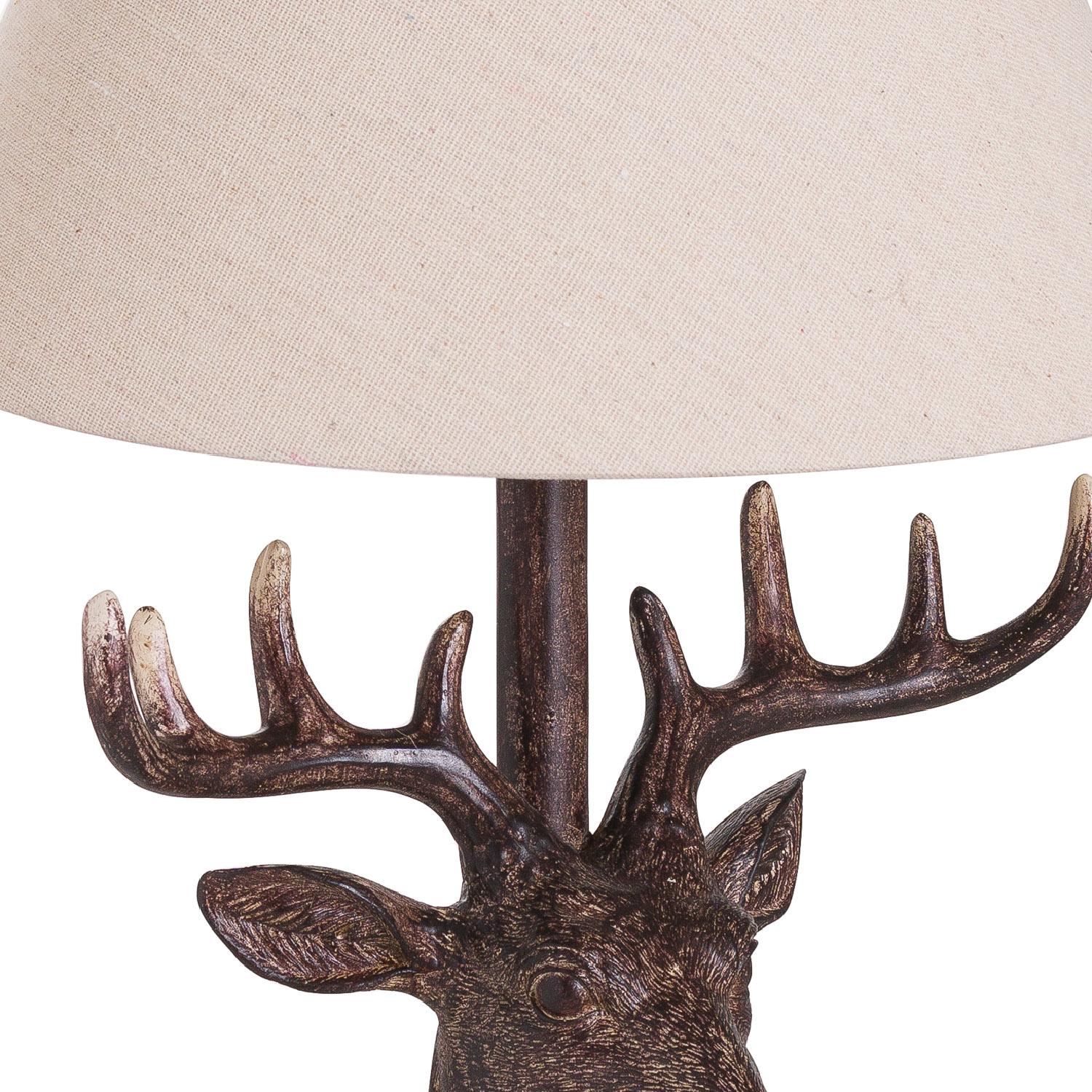 Close up of neutral linen shade of a rustic table lamp with a resin stag head base.