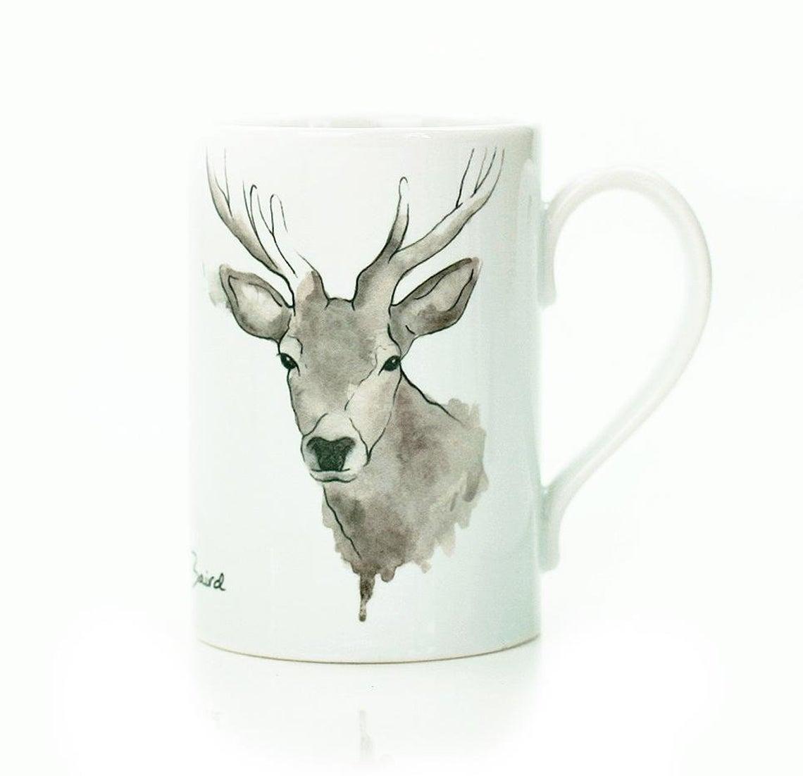 A white porcelain mug with a hand painted highland stag on the front.