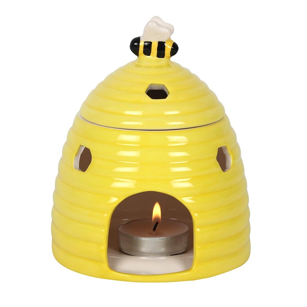 Yellow ceramic oil burner & wax warmer in the shape of a beehive with a bee on the lid and honeycomb shaped cutouts.
