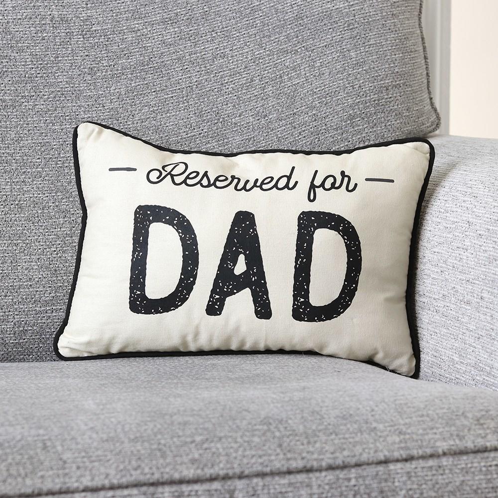 White rectangular canvas cushion with black piping trims border and 'Reserved for Dad' text, shown on a grey sofa.