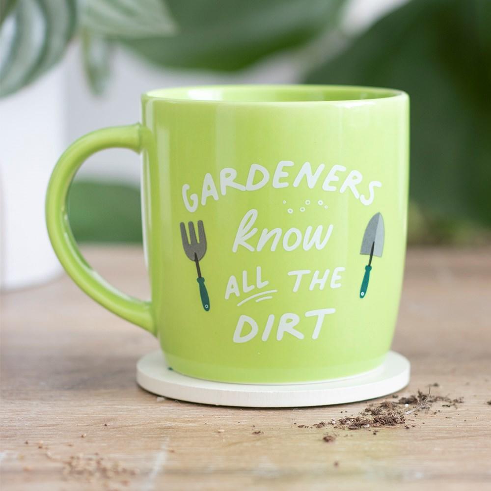 Lime green ceramic mug with garden tool designs and 'Gardeners know all the dirt text', shown with a garden background.