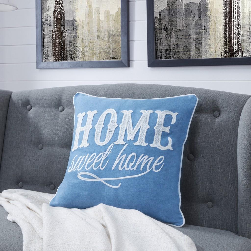 Cotton embroidered throw cushion in blue with white piping trims boarder and 'Home sweet home' text, on a grey sofa.