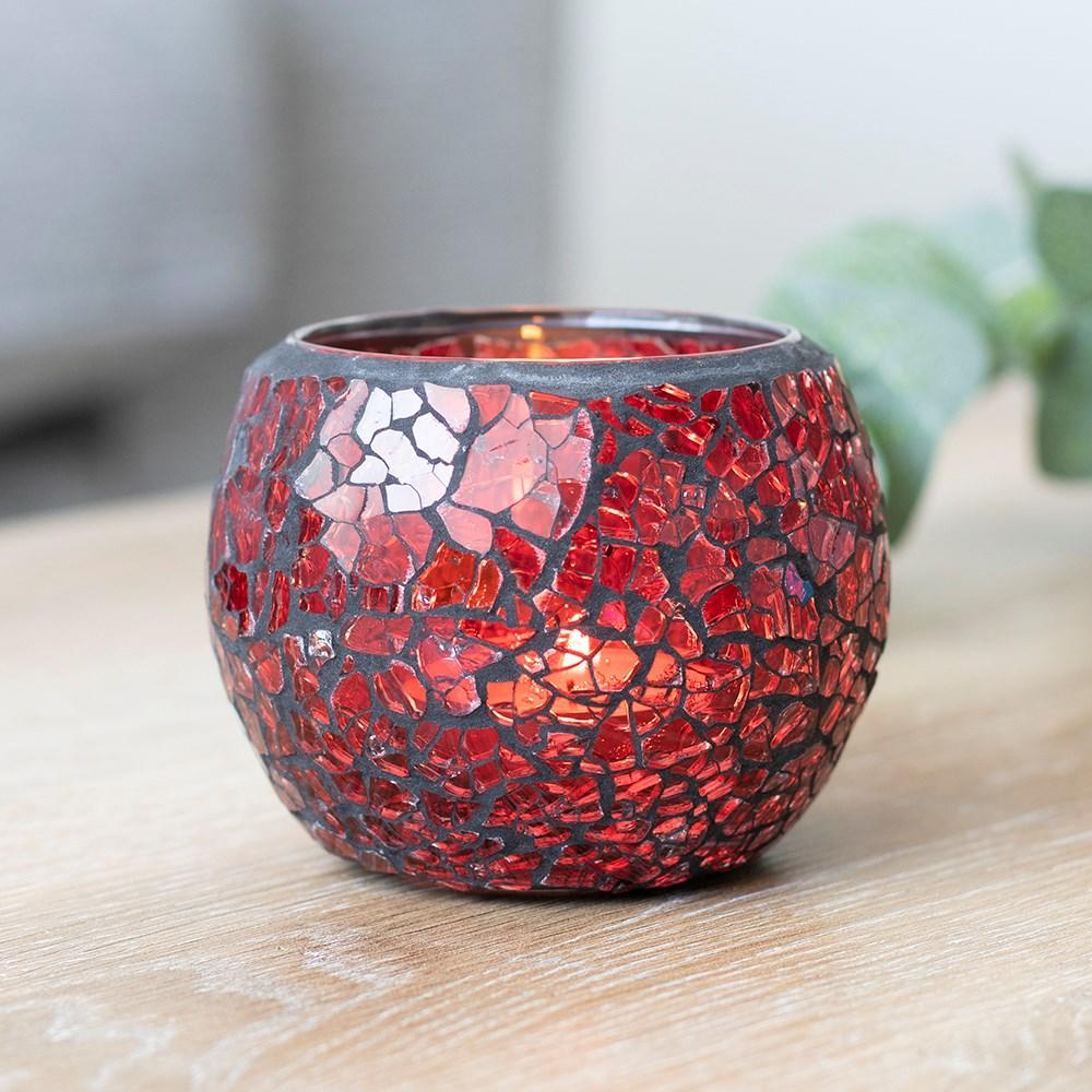 A single small red candle holder with a crackle effect and a subtle sparkle when it catches the light, on a wooden surface.