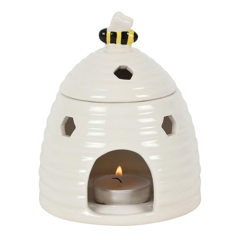 White beehive ceramic oil burner & wax warmer in the shape of a beehive with a bee on the lid and honeycomb shaped cutouts.
