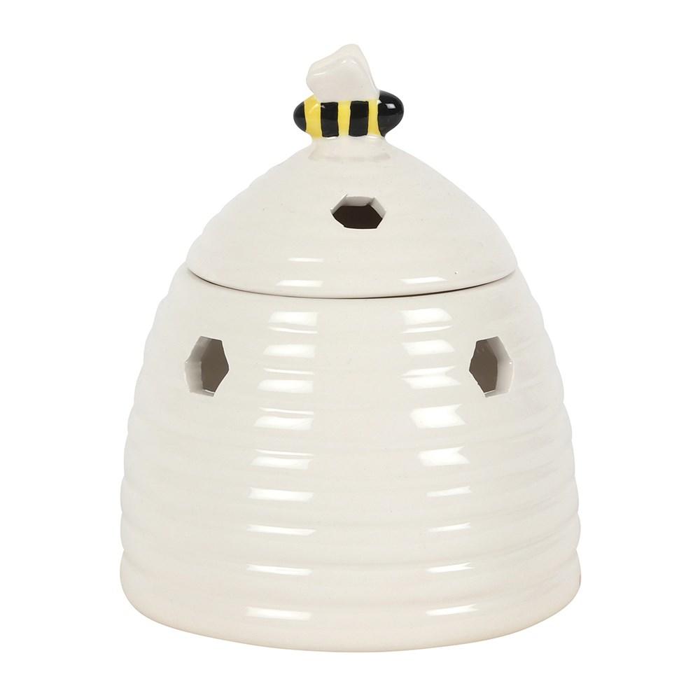 White ceramic oil burner & wax warmer in the shape of a beehive with a bee on the lid & honeycomb shaped cutouts, rear view.
