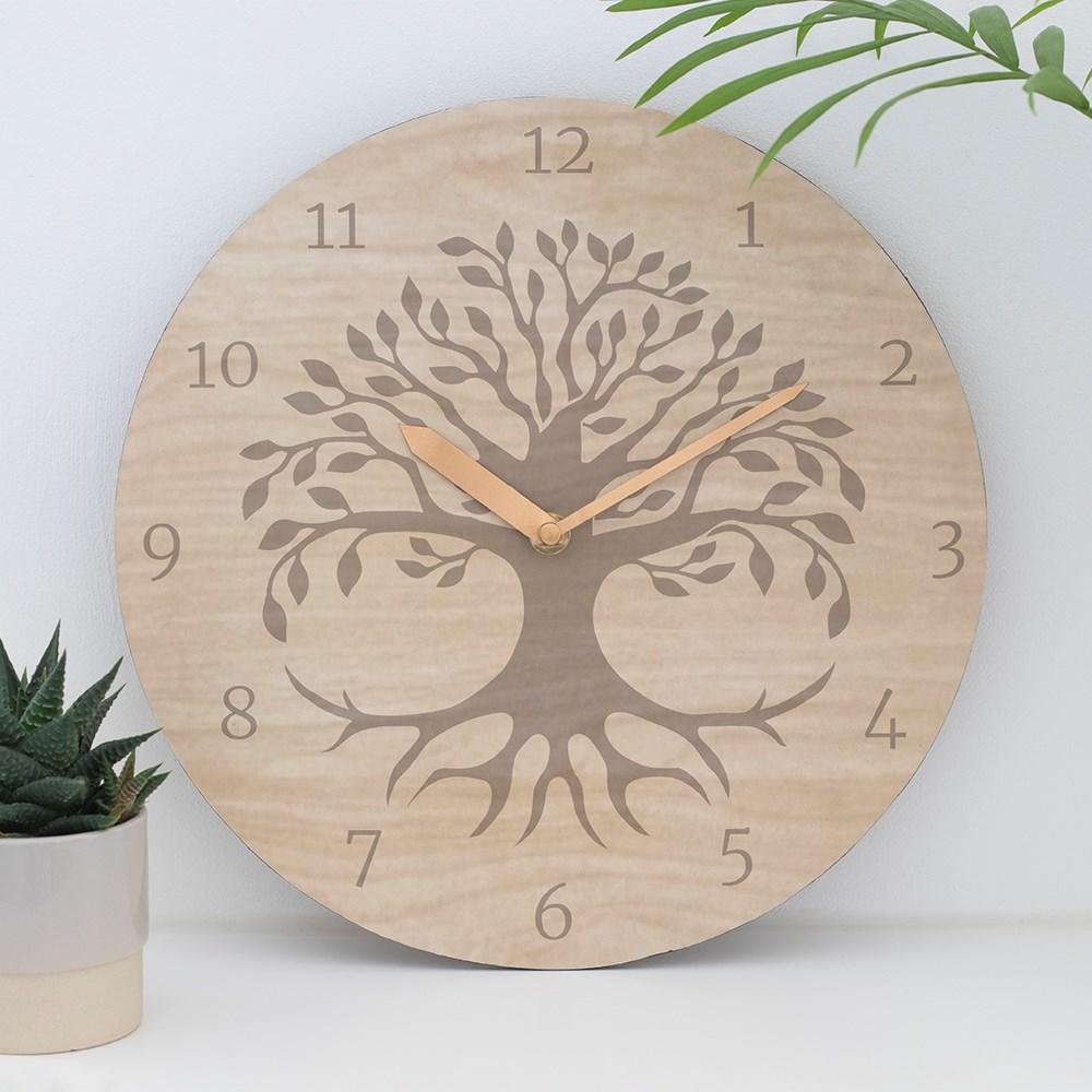 29cm round MDF clock featuring a light brown tree of life silhouette on a wood effect background, with white wall and plants.