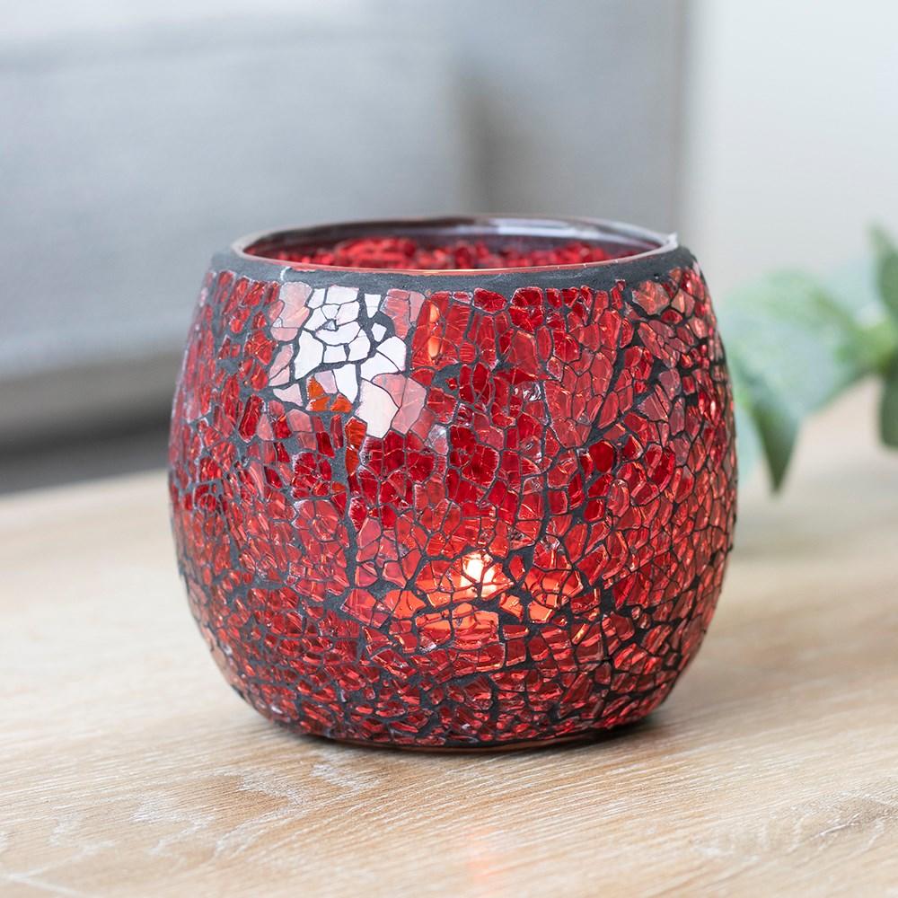 A large red candle holder with a crackle effect and a subtle sparkle when it catches the light, shown on a wooden table.
