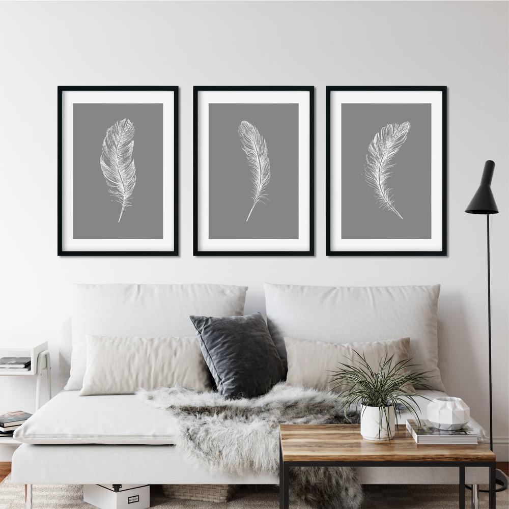 Set Of 3, dark grey feather A3 wall prints, on a grey wall in a living room setting.