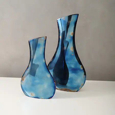 Two metallic blue metal vases, one large and one small.