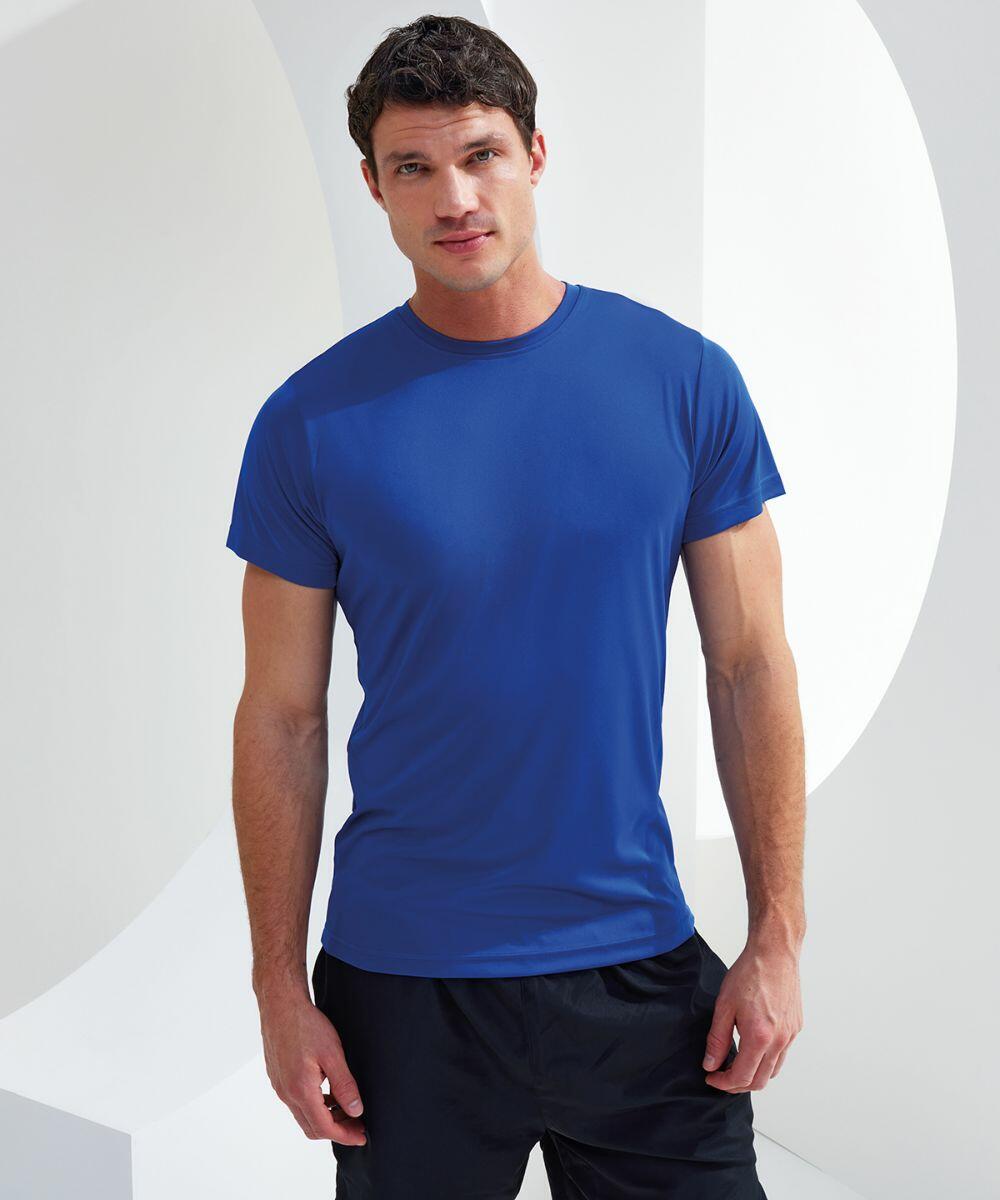 Man standing against a white geometric background wearing a blue TR501 t-shirt by Tri-Dri and black pants. He is looking at the camera with a neutral expression.