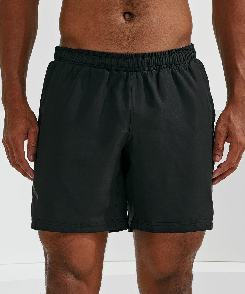 A person standing, wearing Tri-Dri TR052 black athletic shorts with an elastic waistband, against a plain white background.