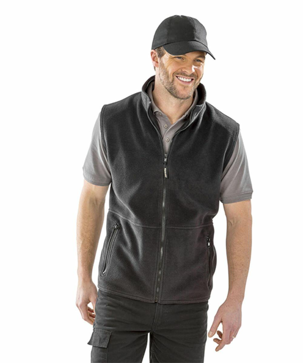 Man wearing a black cap, gray polo shirt, and Result RC036 black zip-up vest, smiling and standing against a white background.