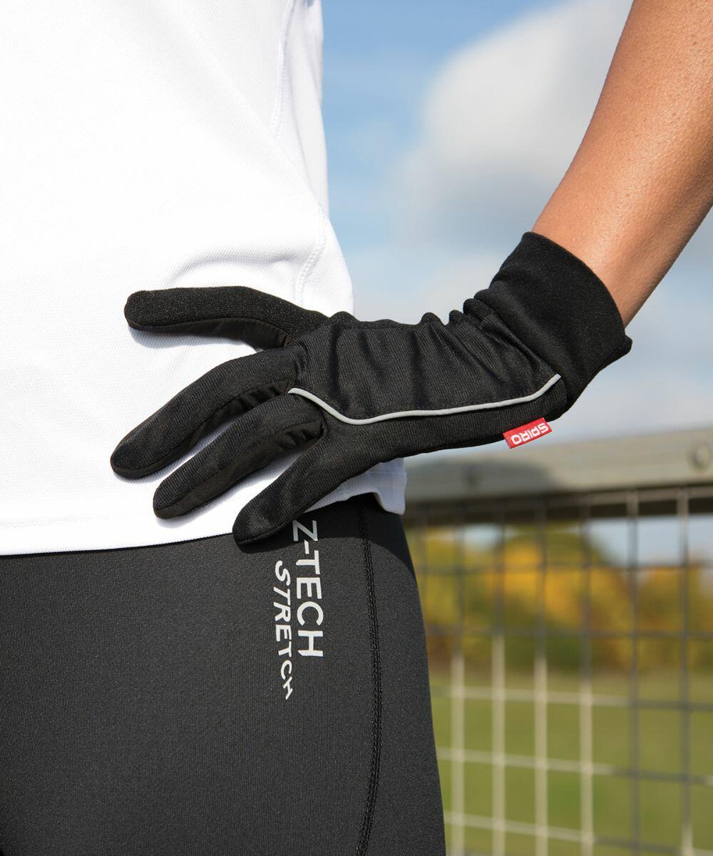 Person wearing black gloves and black athletic pants with "Spiro S267X" printed on the side, standing outdoors with a blurred background.