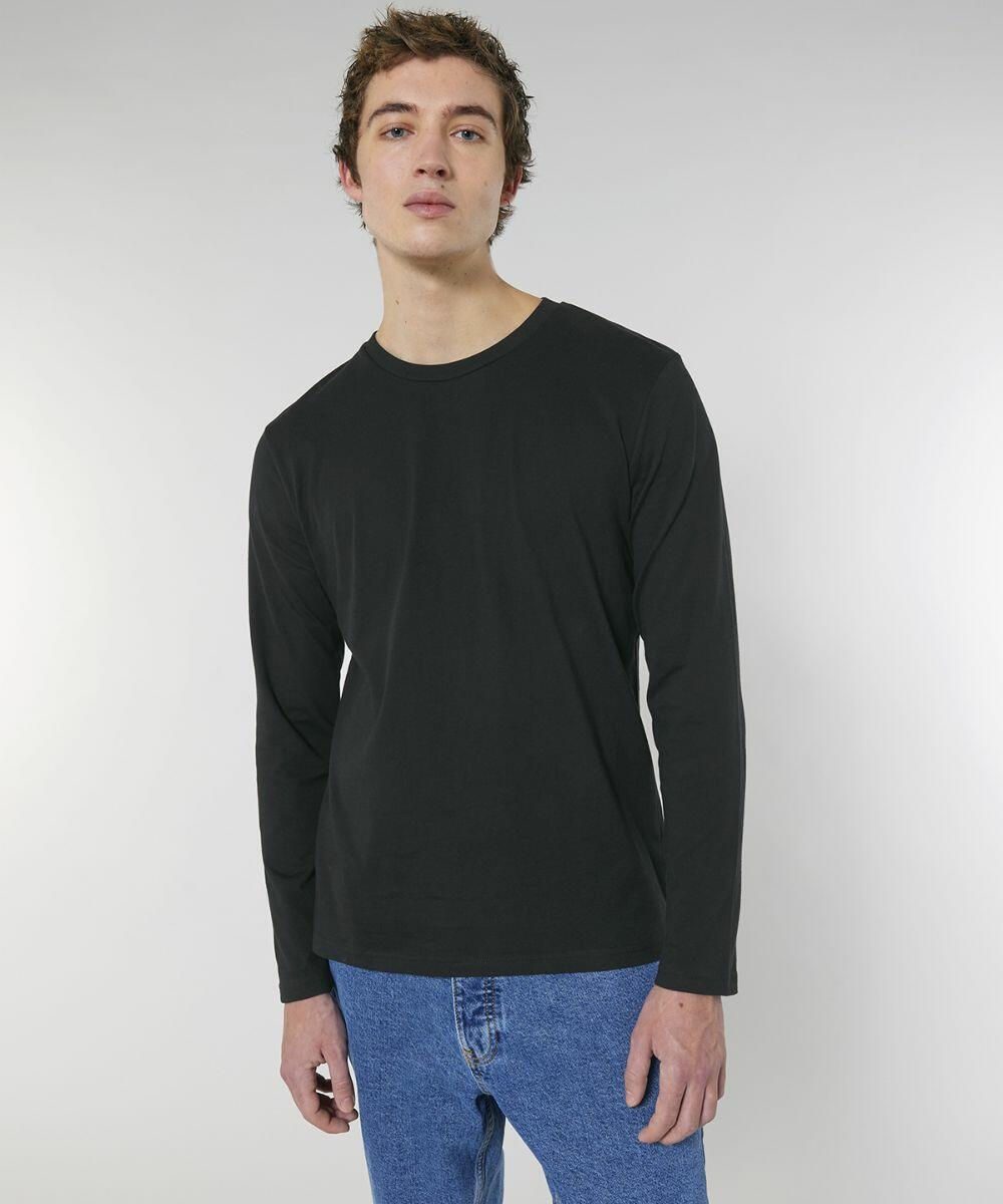 Person standing against a plain background, wearing a black Stanley/Stella SX016 long-sleeve shirt and blue jeans.