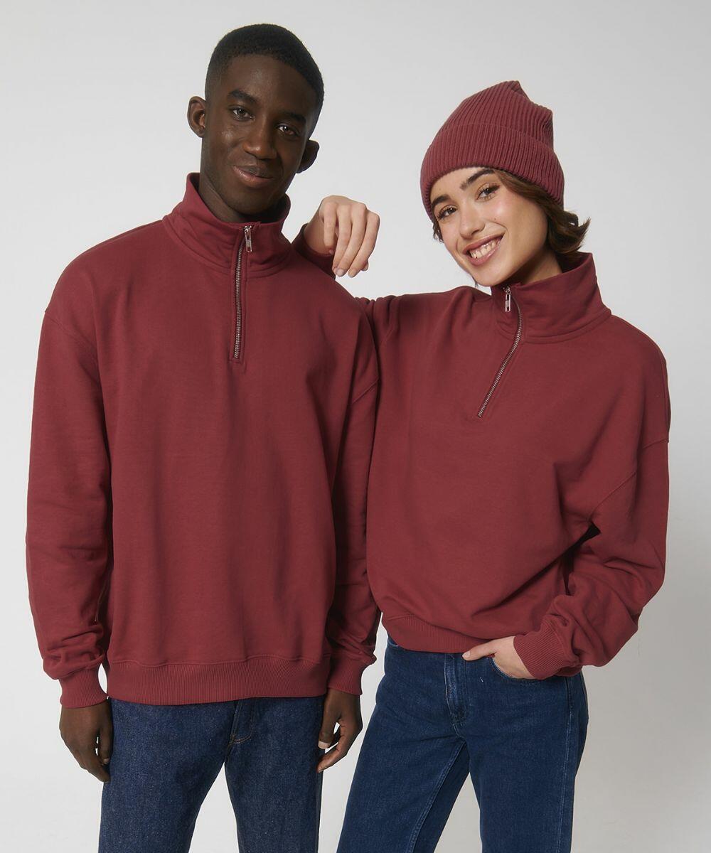 Two people standing side by side, wearing maroon zip-up Stanley/Stella SX216 sweatshirts. The person on the left has a hand in their pocket, and the person on the right is wearing a matching beanie.