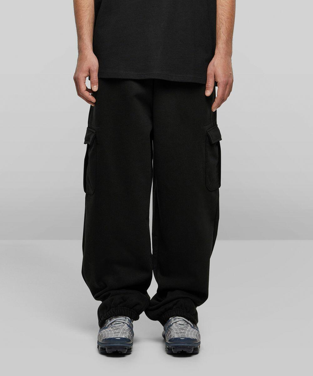 Person wearing black cargo pants and gray sneakers (Build Your Brand BY258), seen from the waist down against a plain background.