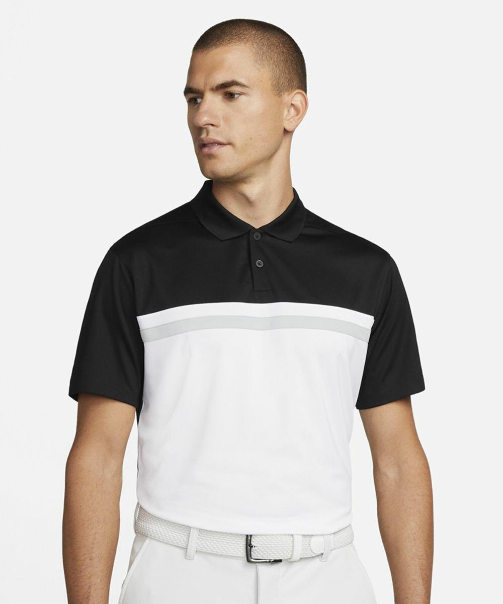 A man wearing a black and white Nike NK343 polo shirt with a horizontal stripe design, white trousers, and a white belt, looking slightly to his left.