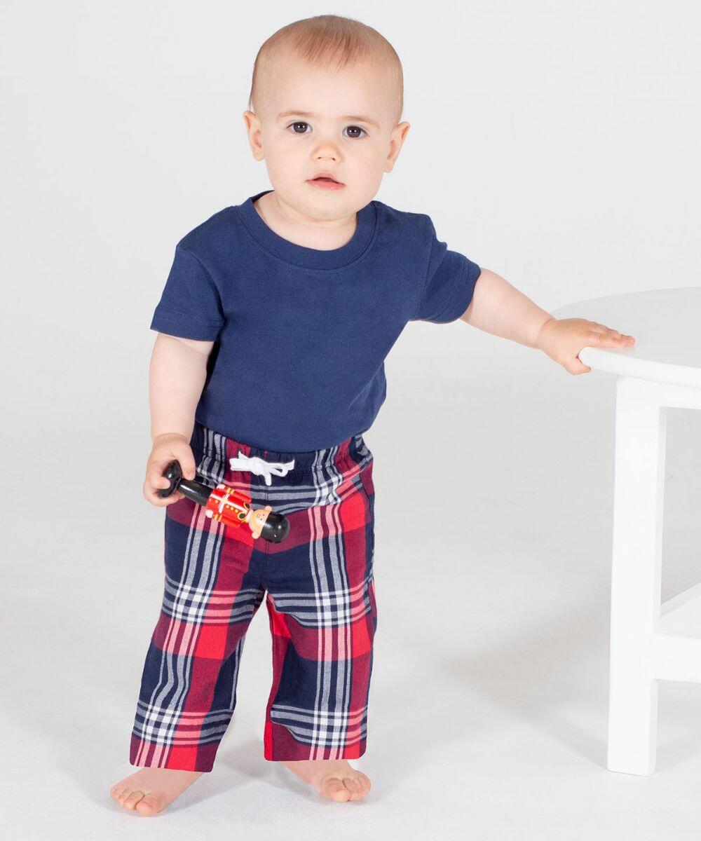 A toddler with short hair stands holding a toy train, wearing a Larkwood LW83T navy blue t-shirt and red plaid pants, next to a white table.