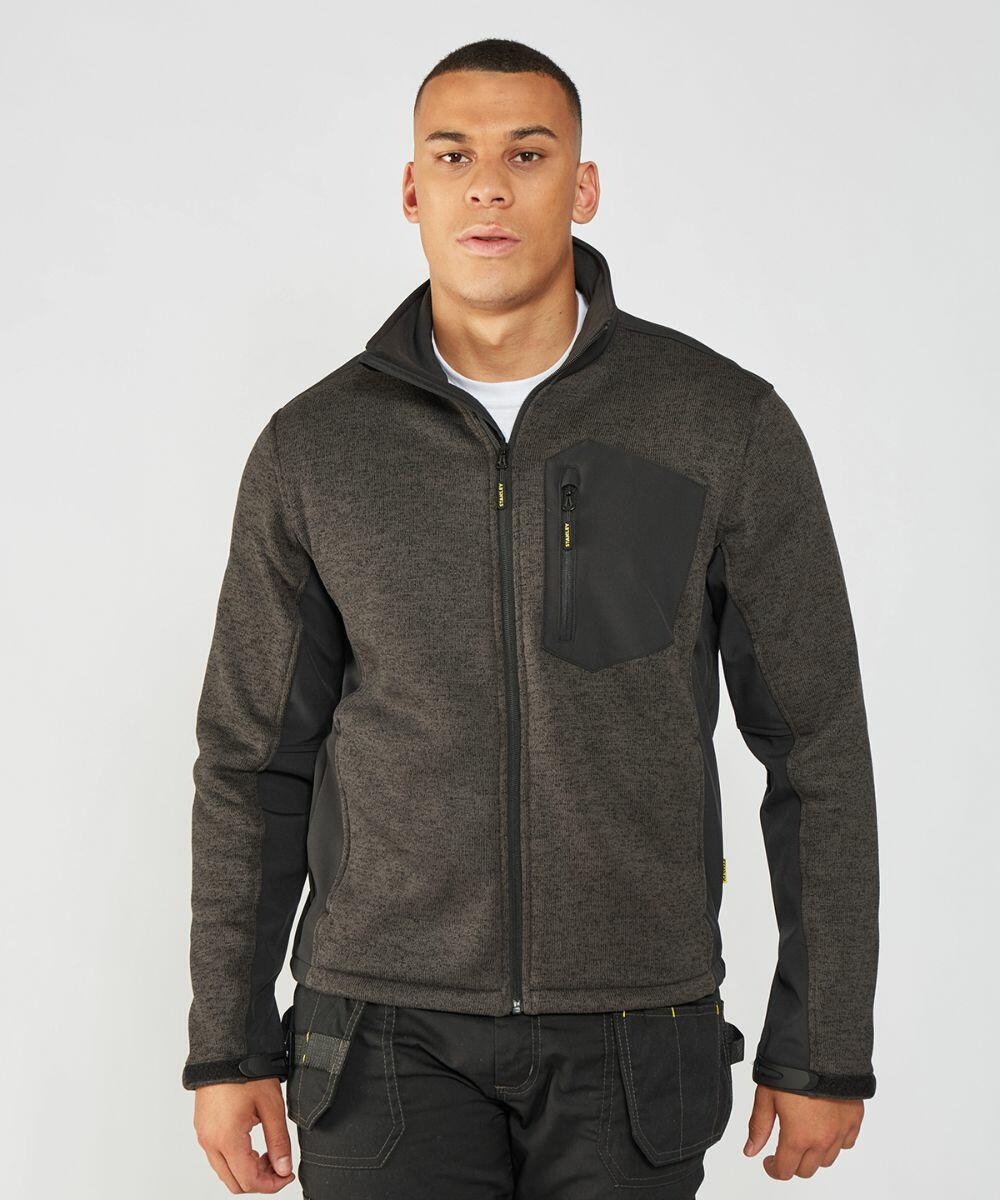 A person is standing against a plain background wearing a grey Stanley Workwear SY022 with black panels and a zippered chest pocket.