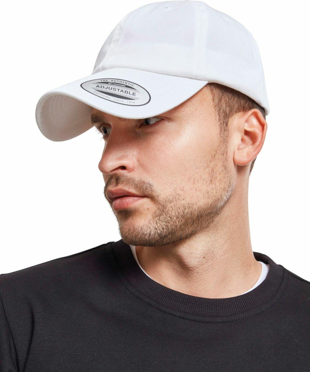 Man in a white cap with a "Flexfit By Yupoong YP097" label, wearing a black shirt, looking to his left.